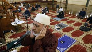 Yusuf Omar melakukan adzan sebelum melaksanakan tarawih pada malam pertama bulan suci Ramadhan di Pusat Komunitas Muslim Chicago, Senin (13/4/2021). (AP Photo/Shafkat Anowar)
