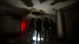 Pengunjung mendengarkan instruksi saat berada didalam rumah hantu Quinta Nova da Assuncao di Belas, Portugal (13/5). Pengunjung akan diajak tur di dalam rumah kosong Quinta Nova da Assuncao. (REUTERS/Rafael Marchante)