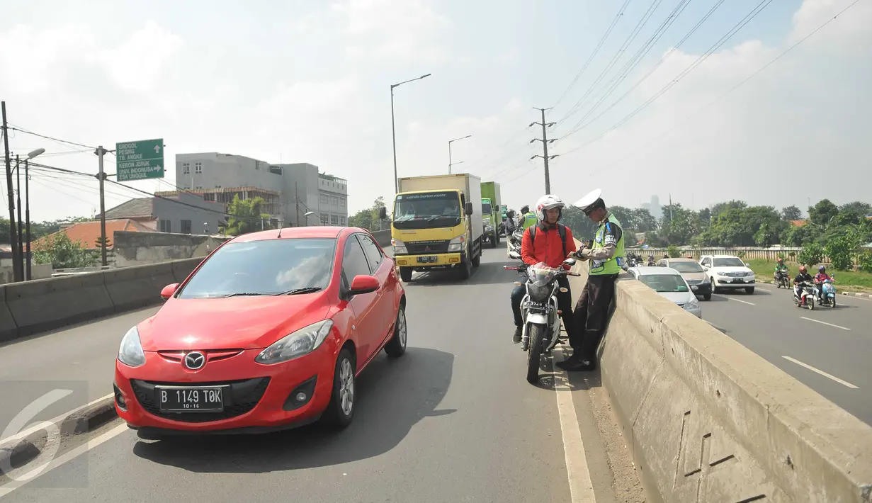 Pengendara motor ditilang petugas di Flyover Pesing arah Kalideres, Jakarta, ketika Operasi Patuh Jaya, Rabu (18/5). Razia dilakukan untuk mengantisipasi sepeda motor yang melawan arus dan masuk jalur flyover. (Liputan6.com/Gempur M Surya)