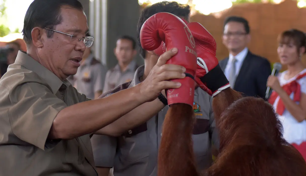 Perdana Menteri Kamboja Hun Sen memegang orangutan setelah pertunjukan kick boxing saat persemian pembukaan Phnom Penh Safari di Kamboja, Sabtu (23/6). (AFP/Tang Chhin Sothy)