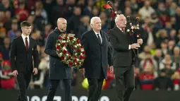 Pelatih manchester United, Erik ten Hag (kedua kiri) di dampingi mantan pemain MU, Alexander Stepney (kedua kanan) dan pemain Akademi MU, Dan Gore membawa karangan bunga untuk diletakkan di tengah lapangan untuk mengenang wafatnya legenda klub, Sir Bobby Charlton, sebelum dimulainya laga matchday ketiga Grup A Liga Champions 2023/2024 antara Manchester United menghadapi FC Copenhagen di Old Trafford Stadium, Rabu (25/10/2023) dini hari WIB. (AP Photo/Dave Thompson)