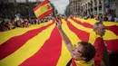 Seorang wanita melambaikan bendera Spanyol ketika orang-orang mengarak bendera Catalonia berukuran raksasa pada perayaan Dia de la Hispanidad  di jalanan Barcelona, Kamis (12/10). (AP / Santi Palacios)