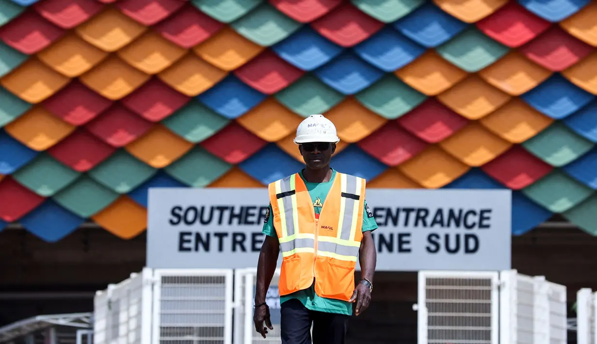Seorang pekerja berjalan keluar dari Stadion Olembe yang terletak di Yaounde, pada 7 Januari 2022. Stadion yang berkapasitas 60.000 penonton tersebut rencananya akan digunakan untuk venue pembukaan Piala Africa 2021. (AFP/Kenzo Tribouillard).