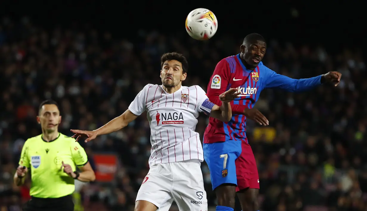 Penyerang Barcelona, Ousmane Dembele berebut bola dengan gelandang Sevilla, Jesus Navas pada pertandingan lanjutan La Liga Spanyol di stadion Camp Nou di Barcelona, Spanyol, Senin (4/4/2022). Barcelona menyamai raihan poin Atletico Madrid dan Sevilla, 57 poin. (AP Photo/Joan Monfort)