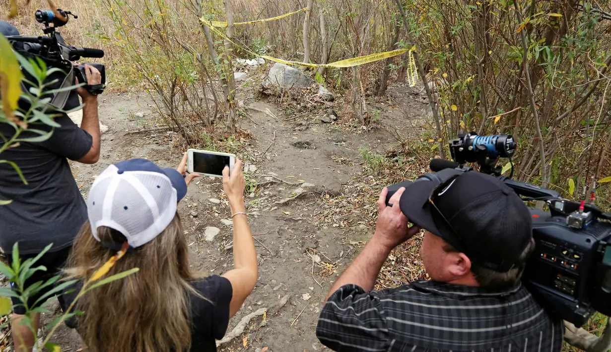 Awak media mengambil gambar lokasi bunuh diri aktor Glee, Mark Salling di area hutan dekat daerah tempat tinggalnya di Los Angeles, Selasa (30/1). Laporan menyampaikan Salling sudah meregang nyawa cukup lama sebelum jenazahnya ditemukan. (AP/Reed Saxon)