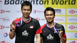 Ganda putra Indonesia Hendra Setiawan dan Mohammad Ahsan menunjukan medali emas usai babak final Kejuaraan Dunia Bulu Tangkis 2019 di St. Jakobshalle, Basel, Swiss, Minggu (25/8/2019). Ahsan/Hendra menjadi juara dunia ganda putra usai menang dengan skor 25-23, 9-21, 21-15. (FABRICE COFFRINI/AFP)