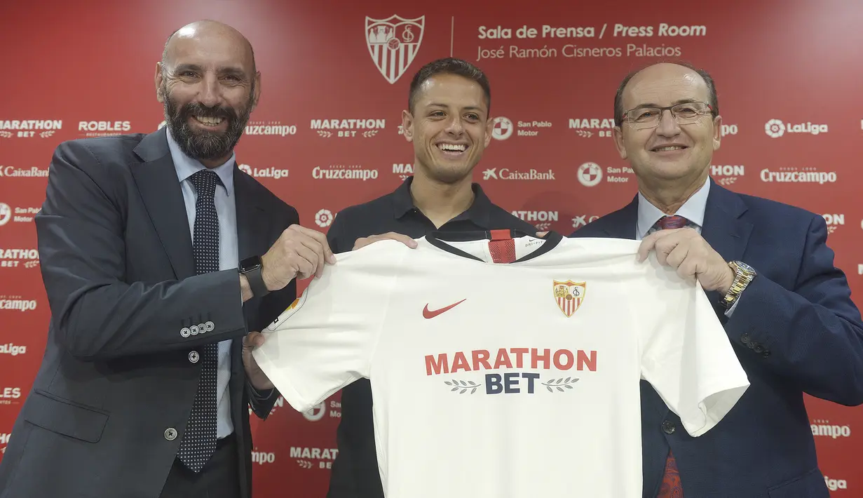 Penyerang Javier Hernandez 'Chicharito' berpose bersama presiden Sevilla Jose Castro (kanan) dan direktur olahraga selama presentasi resminya di Sport City of Sevilla (2/9/2019). Pemain asal Meksiko ini menandatangani kontrak berdurasi tiga tahun bersama Los Rojiblancos. (AFP Photo/Cristina Quicler)