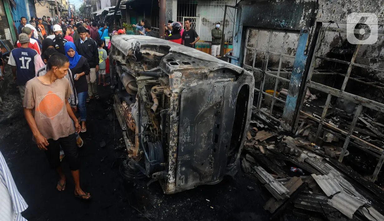 Warga melihat kondisi kendaraan dan rumah yang hangus akibat kebakaran Depo Pertamina Plumpang, Koja, Jakarta Utara, Sabtu (4/3/2023). Si jago merah yang membara melahap belasan korban jiwa, rumah warga, hingga kendaraan bermotor habis tak bersisa. (merdeka.com/Arie Basuki)