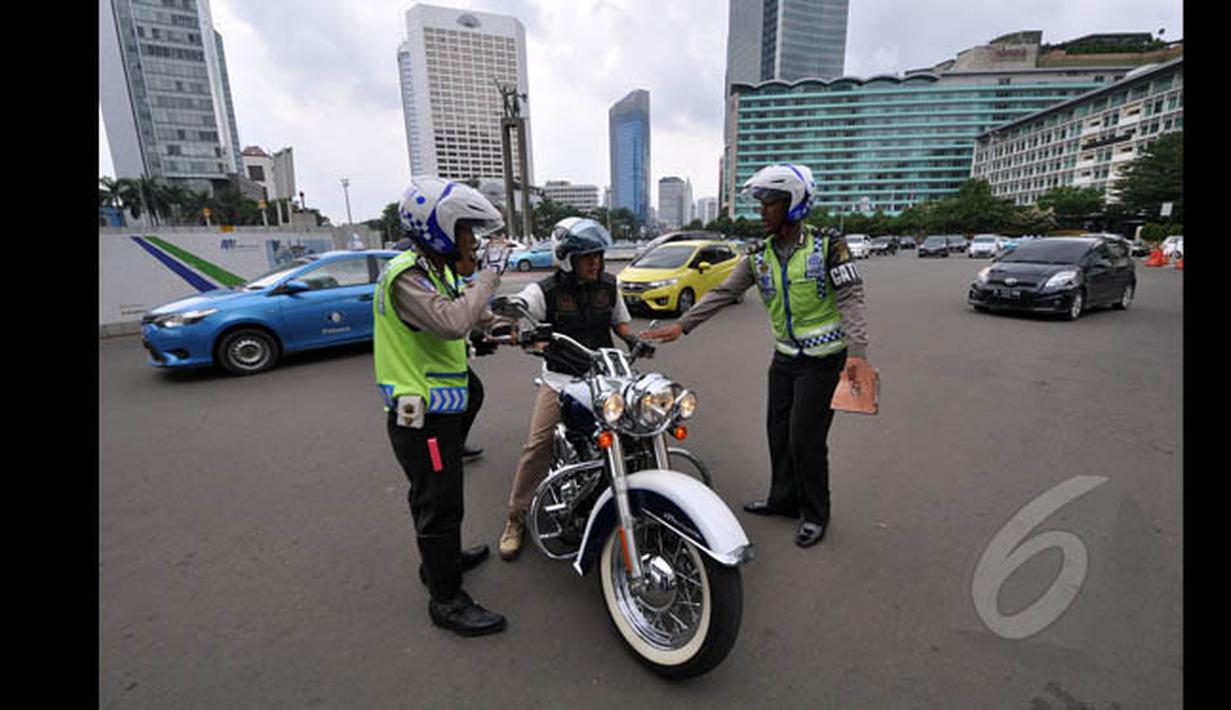 Mulai hari Minggu (18/1/2015), petugas kepolisian memberikan sanksi berupa denda senilai Rp 500 ribu bagi pemotor yang nekat melintasi Jalan MH Thamrin-Medan Merdeka Barat, Jakarta. (Liputan6.com/Miftahul Hayat)