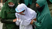 Polisi syariat membawa terpidana kasus zina untuk menjalani hukuman cambuk di halaman Masjid Al-Munawarah, Kota Jantho, Aceh Besar,  Jumat (9/4/2020). Pasangan terpidana yang terbukti melanggar Syariat Islam dalam kasus zina itu masing masing menjalani sebanyak 100 cambuk. (CHAIDEER MAHYUDDIN/AFP)