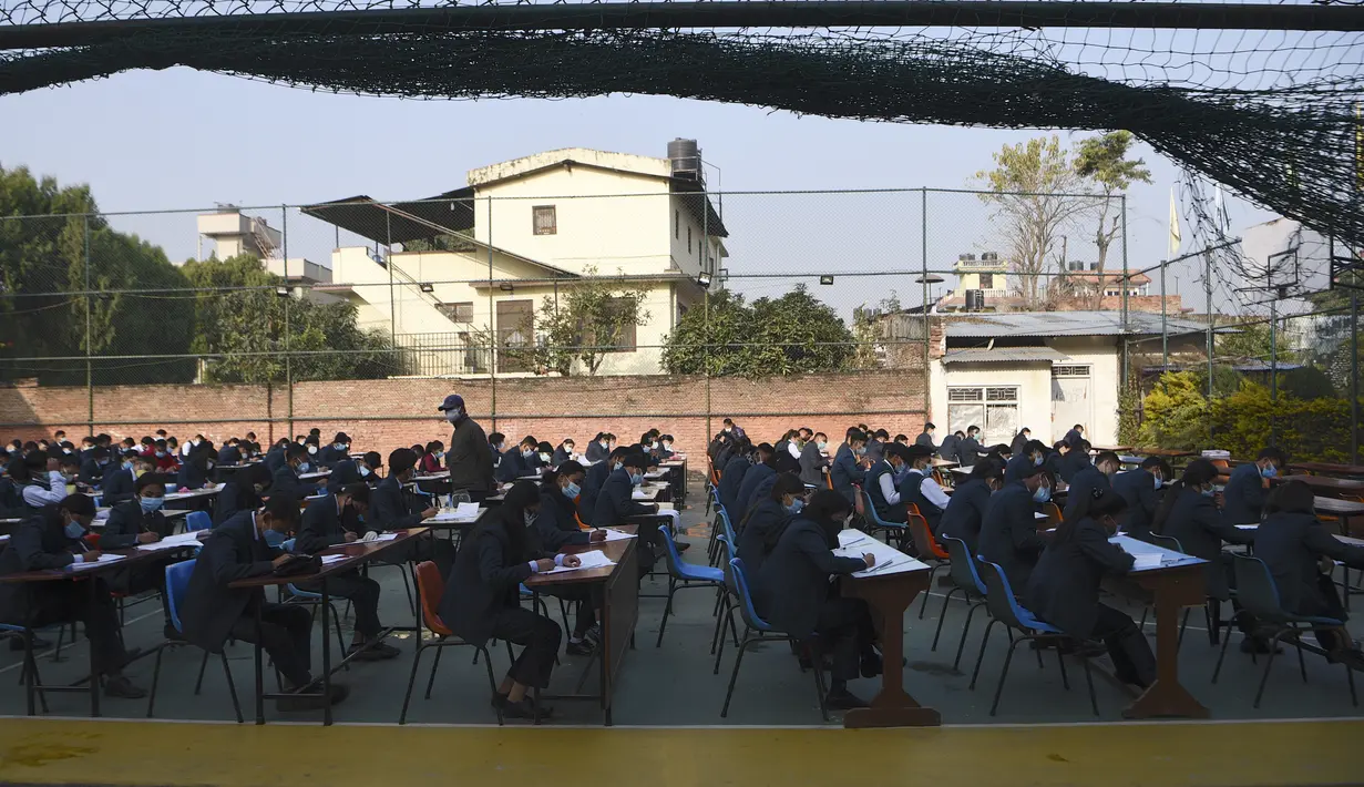 Siswa yang mengenakan masker mengikuti ujian kenaikan kelas XII di lapangan sekolah di Kathmandu, Nepal, Senin (23/11/2020). Nasib sekitar 450.000 siswa kelas XII digantung akibat COVID-19 saat ujian yang dijadwalkan mulai 20 April ditunda karena lockdown pada 24 Maret lalu. (PRAKASH MATHEMA/AFP)