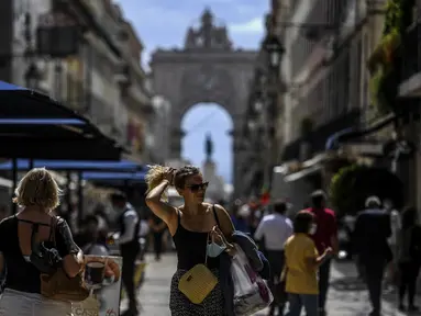 Orang-orang berjalan menyusuri jalan di depan lengkungan Rua Augusta di pusat kota Lisbon, Portugal, Senin (13/9/2021). Portugal hari ini mengakhiri aturan wajib penggunaan masker di jalan-jalan. (PATRICIA DE MELO MOREIRA / AFP)