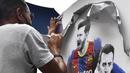 Pekerja melepas poster yang menampilkan pemain depan Argentina, Lionel Messi di pintu masuk Stadion Camp Nou, Barcelona pada Selasa, 10 Agustus 2021. Lionel Messi resmi meninggalkan Barcelona akibat masalah finansial klub dan peraturan dari Liga Spanyol. (AFP/Pau Barrena)