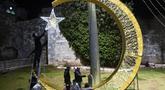 Seorang pria Palestina menggantungkan lampu hias untuk menyambut bulan suci Ramadhan, tepat di luar Kota Tua Yerusalem, Selasa, 21 Maret 2023. (AP Photo/Mahmoud Illean)