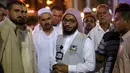 Jemaah haji berbincang dengan seorang penerjemah di kota suci Islam, Makkah, Arab Saudi, 17 Agustus 2018. Para penerjemah ini bisa dicirikan dengan pria yang memakai rompi abu-abu, dan di dadanya dibordir nama bahasa yang dia kuasai. (AFP/AHMAD AL-RUBAYE)