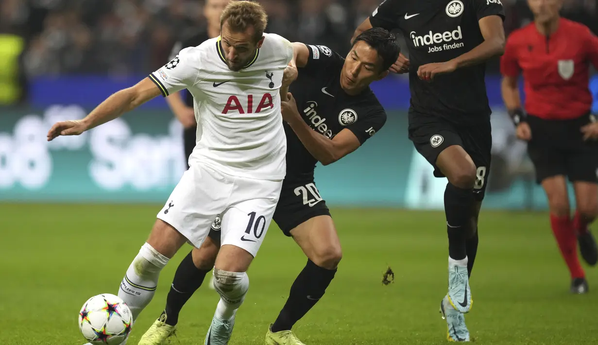 Penyerang Tottenham Hotspur Harry Kane berebut bola dengan bek Eintracht Frankfurt Makoto Hasebe  pada laga lanjutan fase Grup D Liga Champions 2022/2023 di Waldstadion, Rabu (5/10/2022) dini hari WIB. Duel Eintracht Frankfurt vs Tottenham Hotspur dalam lanjutan Liga Champions berakhir tanpa pemenang. (AP Photo/Michael Probst)