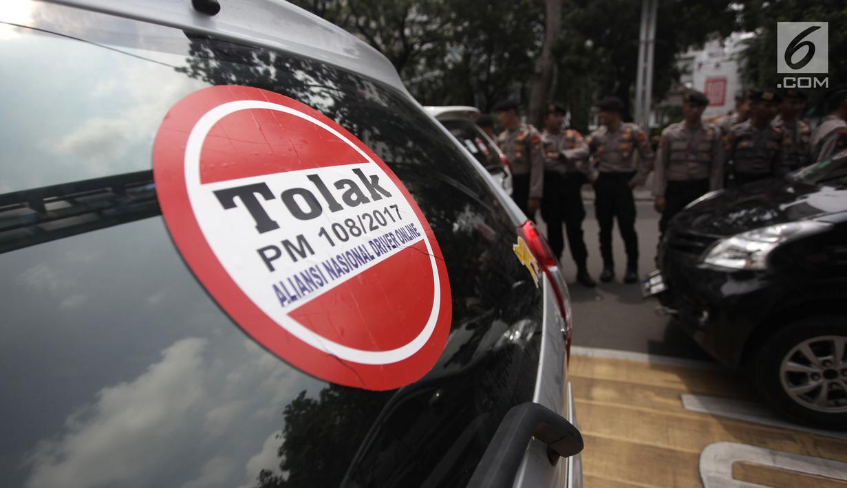 Striker penolakan Permenhub Nomor 108 terpasang di mobil sopir taksi online yang terparkir di Jalan Medan Merdeka Barat, Jakarta, Rabu (14/2). Para pengemudi menolak Permenhub Nomor 108 karena dianggap memberatkan. (Liputan6.com/Arya Manggala)