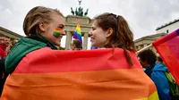 Dua wanita berselimut bendera pelangi saat demontrasi kaum LGBT di depan Gerbang Brandenburg di Berlin (30/6). Sebanyak 393 anggota parlemen Jerman menyetujui pernikahan sesama sejenis, dan 226 anggota lainnya menolaknya. (AFP Photo/Tobias Schwarz)