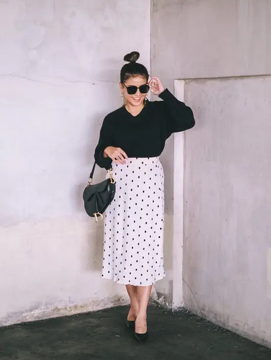 Gaya parisian chic dengan rok midi polkadot dan sweate lengkap dengan handbag Saddle (Foto: Instagram @awkarin)