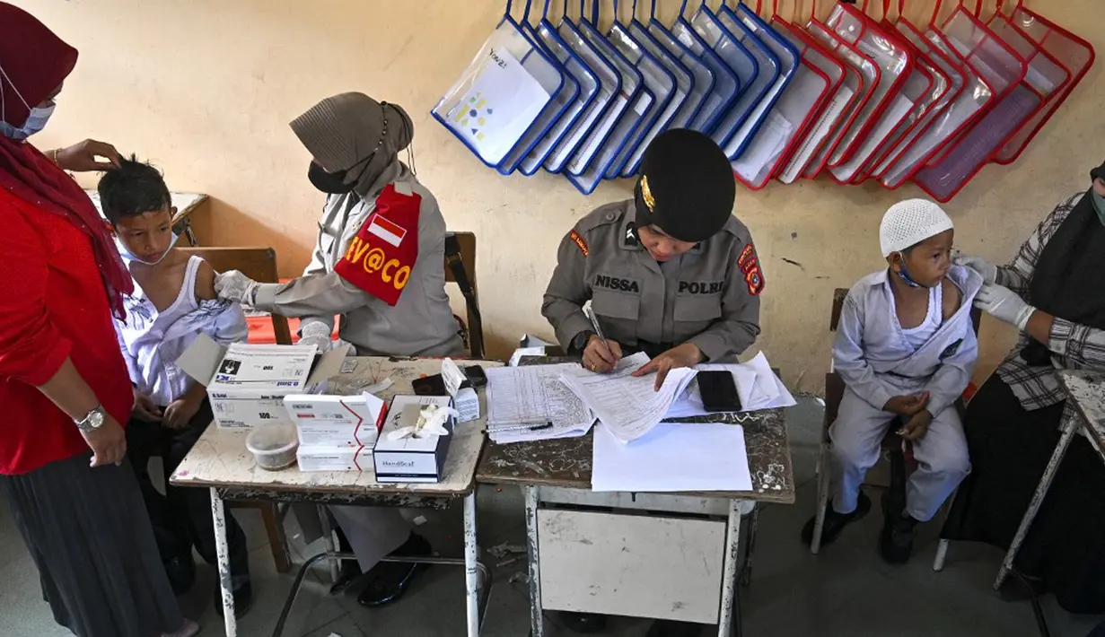 Para siswa menerima vaksin virus corona COVID-19 Sinovac di sebuah sekolah dasar di Darul Imarah, Kabupaten Aceh Besar, Provinsi Aceh, 14 Januari 2022. (CHAIDEER MAHYUDDIN/AFP)