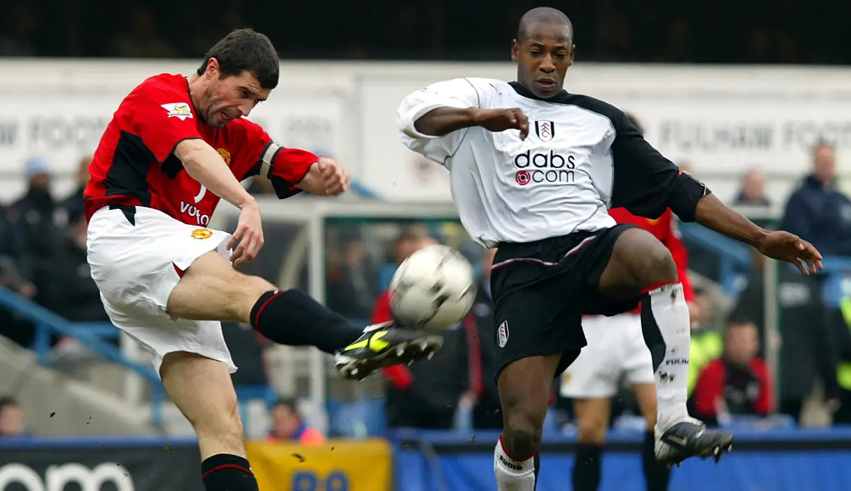 Gelandang Manchester United, Roy Keane (kiri) berusaha membuang bola dari ancaman striker Fulham, Luis Boa Morte pada laga Liga Inggris 2003/2004 di Loftus Road, London (28/2/2004). Roy Keane yang total membela Manchester United selama hampir 13 musim mulai 1993/1994 hingga tengah musim 2005/2006, didatangkan Setan Merah dari Nottingham Forest yang harus terdegradasi pada akhir musim 1992/1993. MU mengeluarkan mahar sebesar 8,5 juta euro untuk sang pemain yang total tampil 478 laga dengan torehan 51 gol dan 38 assist. (AFP/Adrian Dennis)