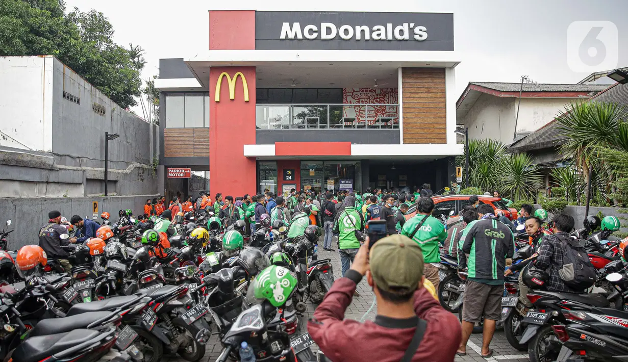 Kerumunan pengemudi ojek online saat antre mengambil pesanan di gerai cepat saji McDonald's Raden Saleh, Jakarta, Rabu (9/6/2021). Puluhan driver ojek online terlihat mengabaikan protokol kesehatan saat mengantre pesanan BTS Meal yang mulai dijual. (Liputan6.com/Faizal Fanani)