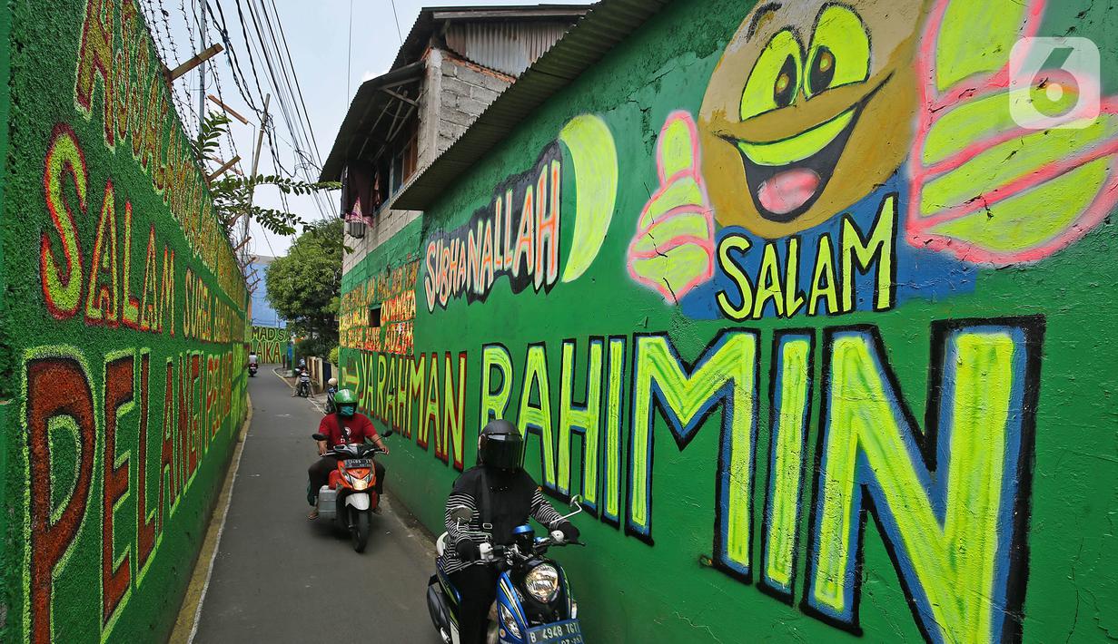 Pengendara melintasi mural bernuansa Islami di Gang Pelangi, kawasan Kalibata, Jakarta, Jumat (23/4/2021). Mural bernuansa Islami tersebut dibuat warga untuk menghiasi dan meramaikan pintu masuk gang dalam rangka menyambut bulan Ramadhan. (Liputan6.com/Herman Zakharia)