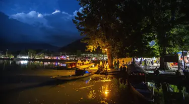 Orang-orang Kashmir duduk di tepi danau Dal pada malam hari di Srinagar, Kashmir yang dikuasai India, Minggu (1/8/2021). Danau terbesar kedua di propinsi Jammu dan Kashmir ini merupakan pusat pariwisata dan rekreasi. (AP Photo/Mukhtar Khan)