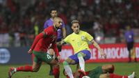 Gelandang Maroko, Sofyan Amrabat, berduel melawan pemain Brasil, Antony dalam laga uji coba di Grand Stade de Tanger, Tangier, Minggu (26/3/2023) pagi WIB. (AP/Mosha'ab Elshamy)