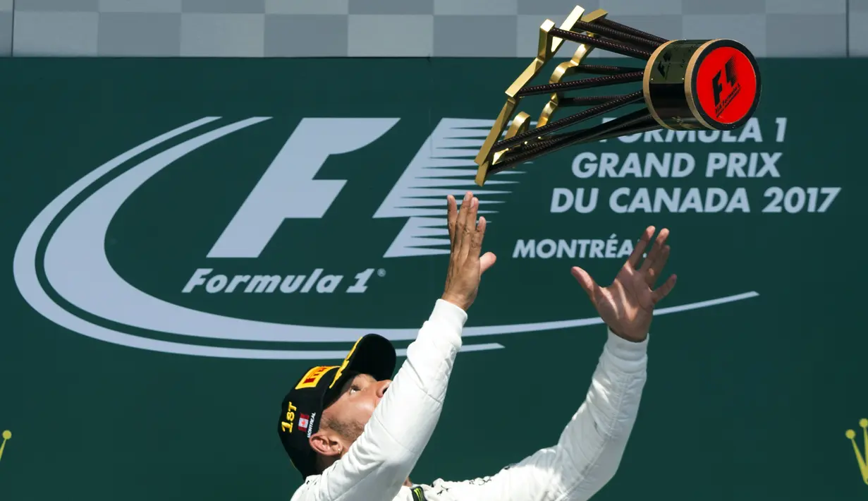 Lewis Hamilton melempar trofi juara setelah menang  pada ajang Formula One Canadian Grand Prix di Montreal, Canada, (11/6/2017).  (Paul Chiasson/The Canadian Press via AP)