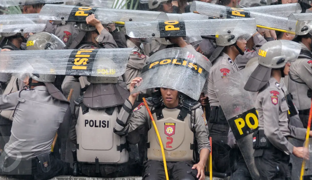 Hujan yang mengguyur di Ibukota tidak menyurutkan petugas kepolisian untuk tetap menjaga aksi Hari Buruh di Jalan Medan Merdeka, Jakarta, Senin (1/5). (Liputan6.com/ Yoppy Renato)