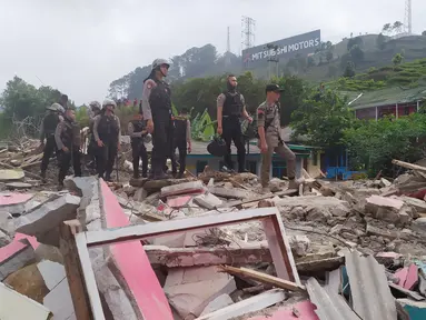 Personel Polres Bogor berdiri di atas sisa reruntuhan bangunan yang dibongkar di Kampung Naringgul, Kabupaten Bogor, Kamis (29/8/2019). Puluhan bangunan rumah yang sebagian merupakan penginapan dan rumah kos-kosan tersebut dibongkar Satpol PP lantaran tidak memiliki izin. (Liputan6.com/Alby Azka)