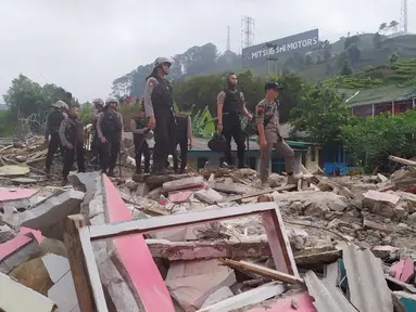 Personel Polres Bogor berdiri di atas sisa reruntuhan bangunan yang dibongkar di Kampung Naringgul, Kabupaten Bogor, Kamis (29/8/2019). Puluhan bangunan rumah yang sebagian merupakan penginapan dan rumah kos-kosan tersebut dibongkar Satpol PP lantaran tidak memiliki izin. (Liputan6.com/Alby Azka)