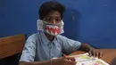 Seorang siswa India mengenakan masker buatannya sendiri saat mendengarkan seorang guru di sebuah sekolah pemerintah di Hyderabad, India, Rabu (4/3/2020). Menurut informasi yang beredar masker tersebut dibuat menggunakan kertas dan di gambar. (AP Photo/Mahesh Kumar A.)