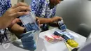 Petugas Bank Indonesia (BI) menghitung uang saat menggelar layanan penukaran uang receh di Lantai 7 SCTV Tower, Jakarta, Jumat (24/6). BI membawa uang Rp 700 juta untuk ditukarkan oleh para karyawan EMTEK Group. (Liputan6.com/Fery Pradolo)