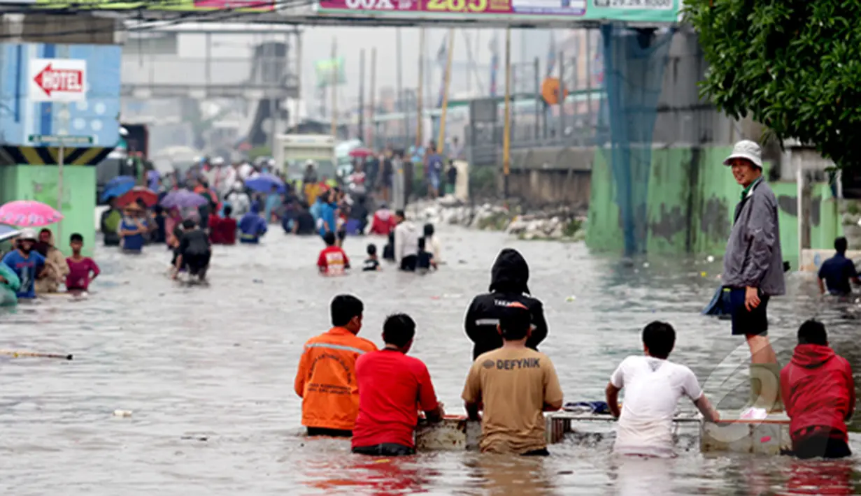 Seorang penguna jasa gerobak saat melintasi banjir di Jalan Gunung Sahari, Jakarta, Senin (6/2/2015). Jasa gerobak Mematok harga Rp. 30 ribu untuk membawa motor sedangkan untuk per orang hanya Rp. 10 ribu. (Liputan6.com/Faizal Fanani)
