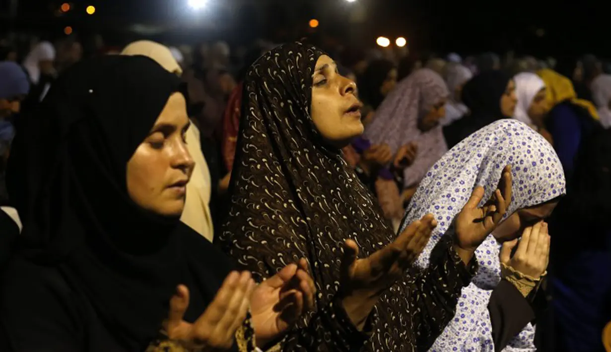 Umat muslim perempuan Palestina  tampak khusyuk memanjatkan doa di depan Kubah Batu, di kompleks Masjid Al Aqsa, Yerusalem, Senin (13/7/2015). Setiap malam Lailatul Qadar, kompleks Masjid Al Aqsa dipenuhi para umat muslim. (AFP PHOTO/Ahmad GHARABLI)