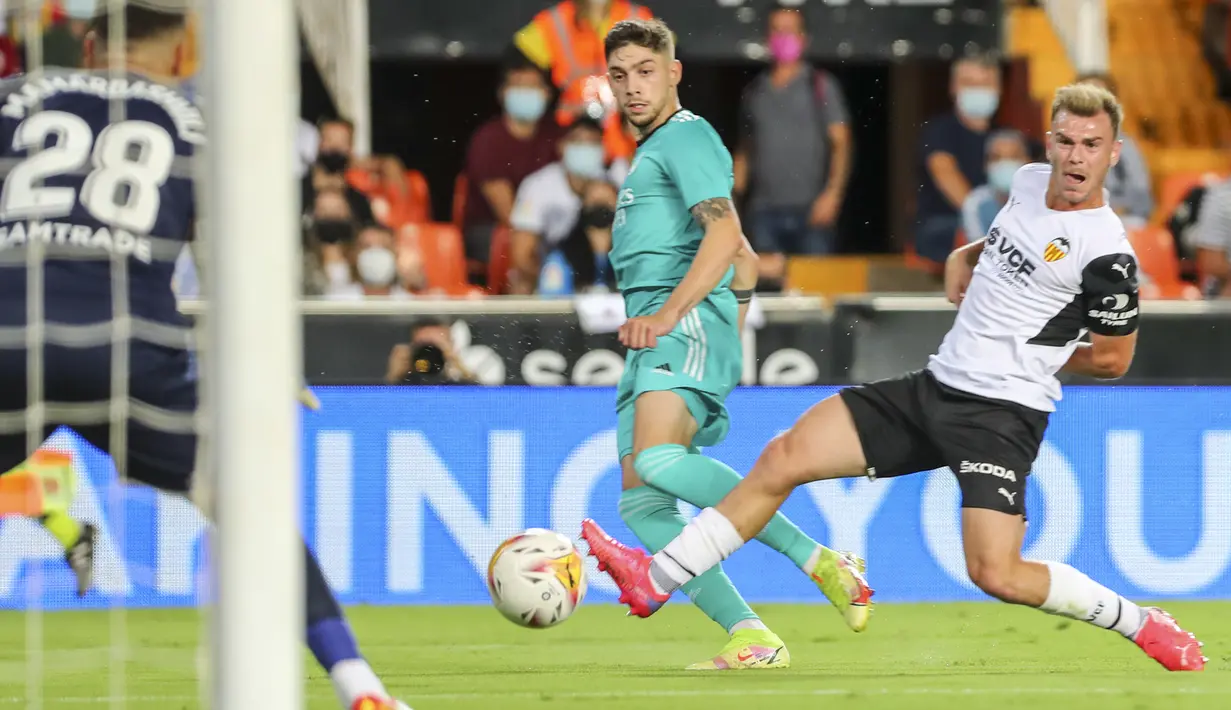Gelandang Real Madrid, Federico Valverde mencoba melakukan tembakan di sebelah bek Valencia, Toni Lato pada lanjutan La Liga di Stadion Mestalla, Senin (20/9/2021) dini hari WIB. Real Madrid menang 2-1 secara dramatis atas Valencia. (AP Photo/Alberto Saiz)