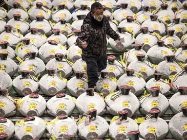 Seorang tengkulak yang mengenakan masker untuk mencegah penularan COVID-19 berjalan melewati deretan tuna beku di Pasar Toyosu, Tokyo, Jepang, 5 Januari 2021. Lelang tuna Tahun Baru tahunan berakhir tanpa perang penawaran yang mencengangkan. (Philip FONG/AFP)