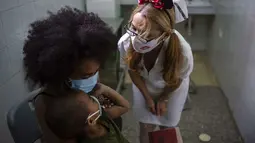 Seorang perawat menghibur anak setelah disuntik dengan dosis vaksin COVID-19 Soberana-02, di sebuah klinik di Havana, Kuba, Kamis (17/9/2021). Pemerintah Kuba memulai vaksinasi Covid-19 bagi anak-anak berusia 2 tahun dengan vaksin buatan dalam negeri. (AP Photo/Ramon Espinosa)