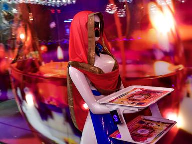 Seorang pelayan robot bernama Ruby menyajikan makanan kepada pelanggan di restoran Drink and Spice Magic, Dubai, 26 Juli 2018. Robot putih biru yang dipercantik dengan syal merah itu mengantar makanan dengan nampan yang mereka bawa. (AFP/GIUSEPPE CACACE)