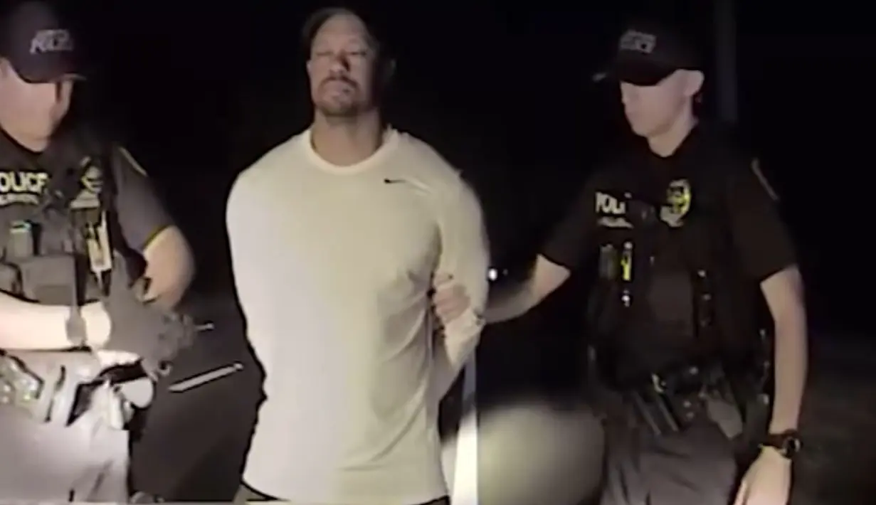Dalam gambar yang diambil dari video terlihat pegolf ternama AS, Tiger Woods ditangkap dua polisi di Jupiter, Florida, 29 Mei 2017. Tiger Woods harus berurusan dengan pihak kepolisian karena menyetir dalam keadaan mabuk. (Jupiter Police Department/via AP)