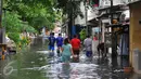 Tampak Warga melawati jalanan yang banjir di kawasan Jakarta Barat, Jumat (26/2). Ketinggian banjir mencapai 50-60cm.  (Liputan6.com/Faisal R Syam)