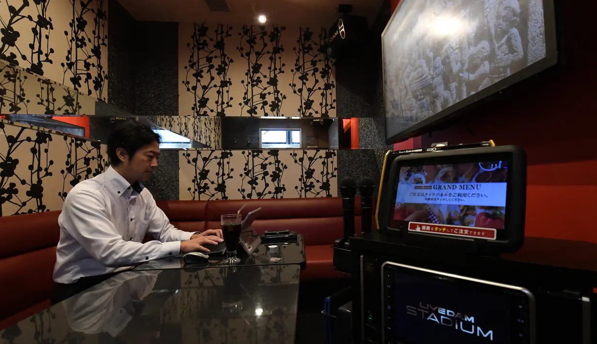 Foto 30 Agustus 2018, pengusaha Hideyuki Aoki bekerja di dalam ruangan karaoke sewaan di Tokyo. Perusahaan karaoke terbesar Jepang, Daiichikosho, menyewakan ruang karaoke untuk tempat kerja para karyawan yang bosan di kantor. (Toshifumi KITAMURA/AFP)