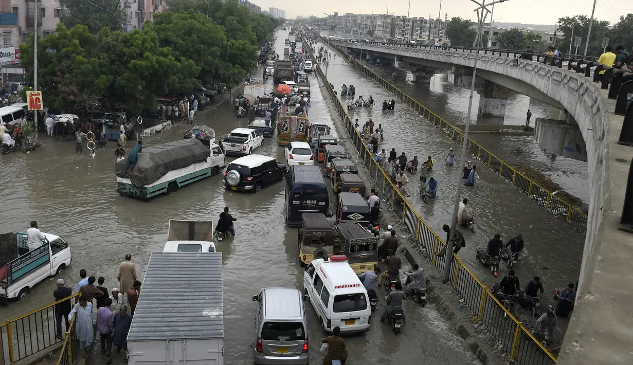 Para pengendara melewati jalan yang banjir di Karachi, Pakistan, Kamis (23/9/2021). Banjir merendam Karachi setelah diguyur hujan deras. (AP Photo/Fareed Khan)