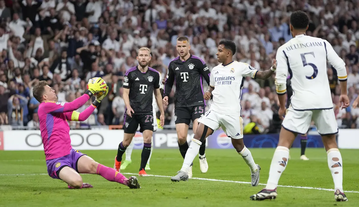 Kiper Bayern Munchen, Manuel Neuer (kiri) berhasil menangkap bola tendangan striker Real Madrid, Rodrygo (tengah) pada laga leg kedua semifinal Liga Champions 2023/2024 di Santiago Bernabeu Stadium, Madrid, Rabu (8/5/2024). (AP Photo/Manu Fernandez)