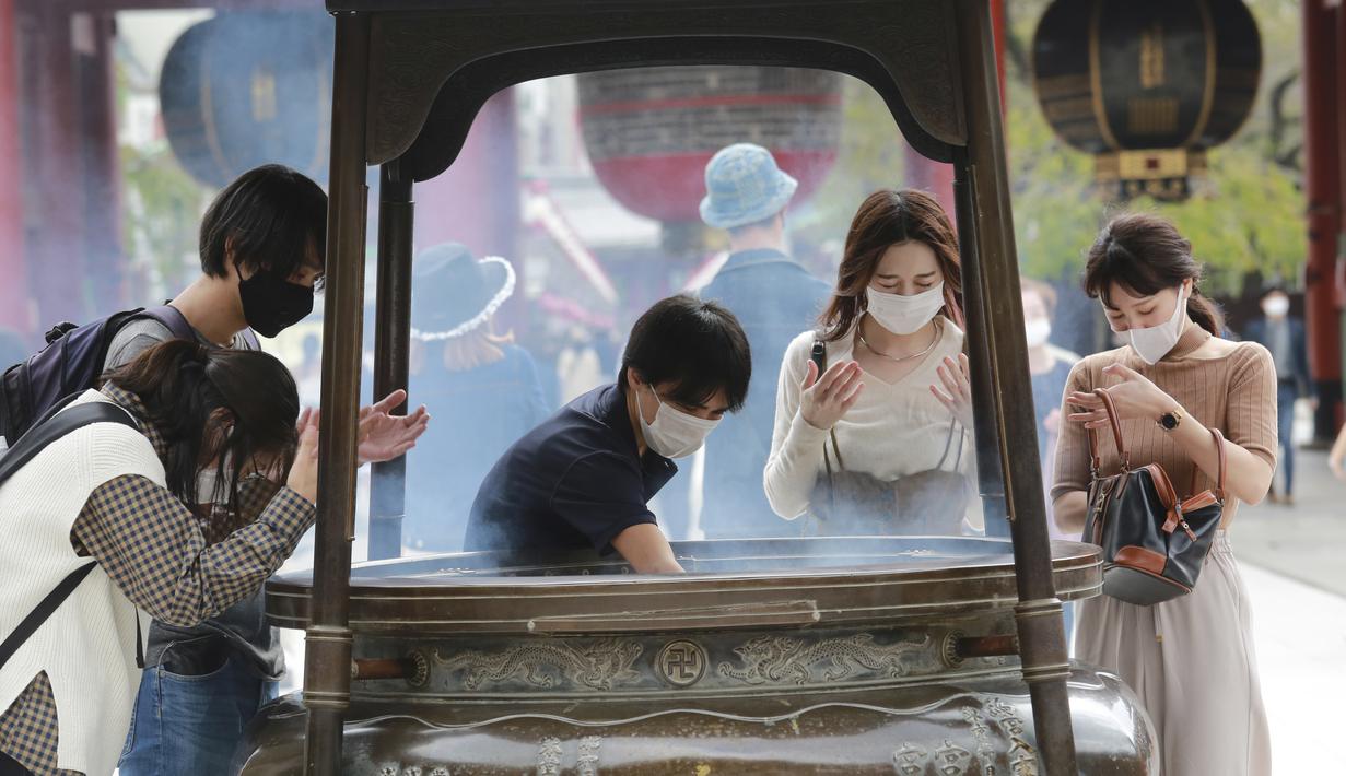 Pengunjung mengenakan masker wajah untuk melindungi dari penyebaran mandi virus corona di spanduk dupa di kuil Sensoji di distrik Asakusa di Tokyo, Rabu, Jepang (14/10/2020). Tokyo mengonfirmasi lebih dari 170 kasus virus corona baru pada hari Rabu. (AP Photo/Koji Sasahara)