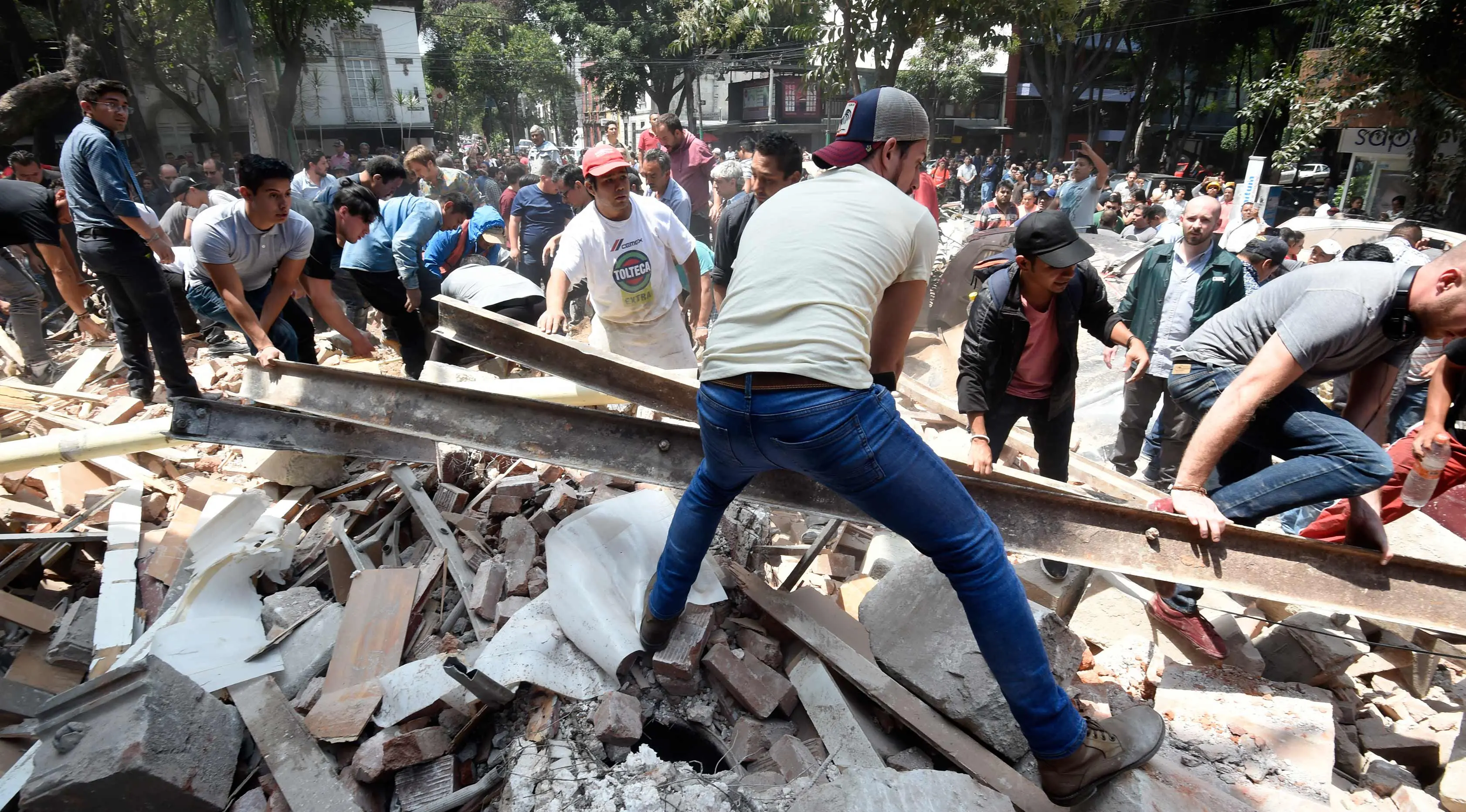 Warga memindahkan puing-puing bangunan untuk mencari korban akibat gempa 7,1 SR di Mexico City, Meksiko (19/9). Sejumlah fasilitas publik seperti bandara, mengalami kerusakan yang signifikan. (AFP Photo/Alfredo Estrella)