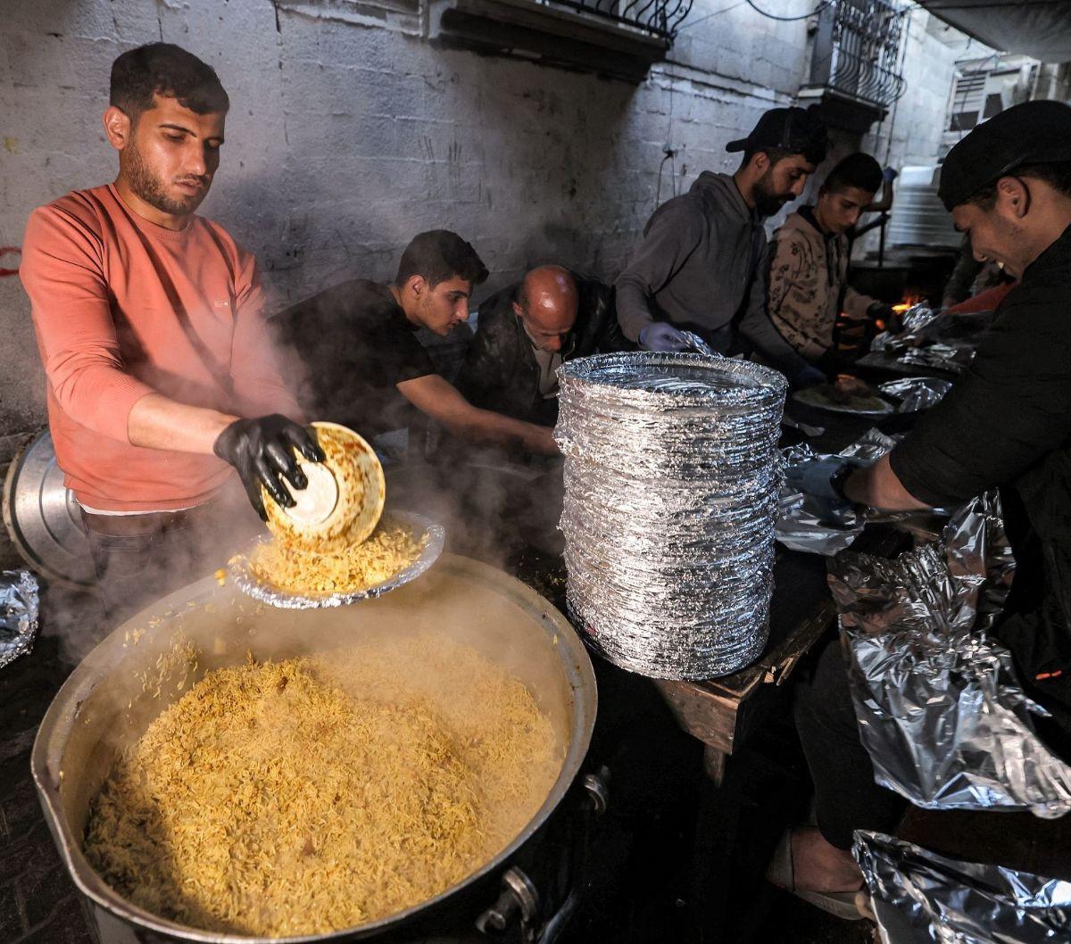 Hidangan itu dimasak oleh relawan dari organisasi kemanusiaan yang juga seorang pengungsi Barbara yang menyajikan makanan bagi orang-orang yang berbuka puasa di bulan suci Ramadan di Rafah.&nbsp;Foto: MOHAMMED ABED / AFP