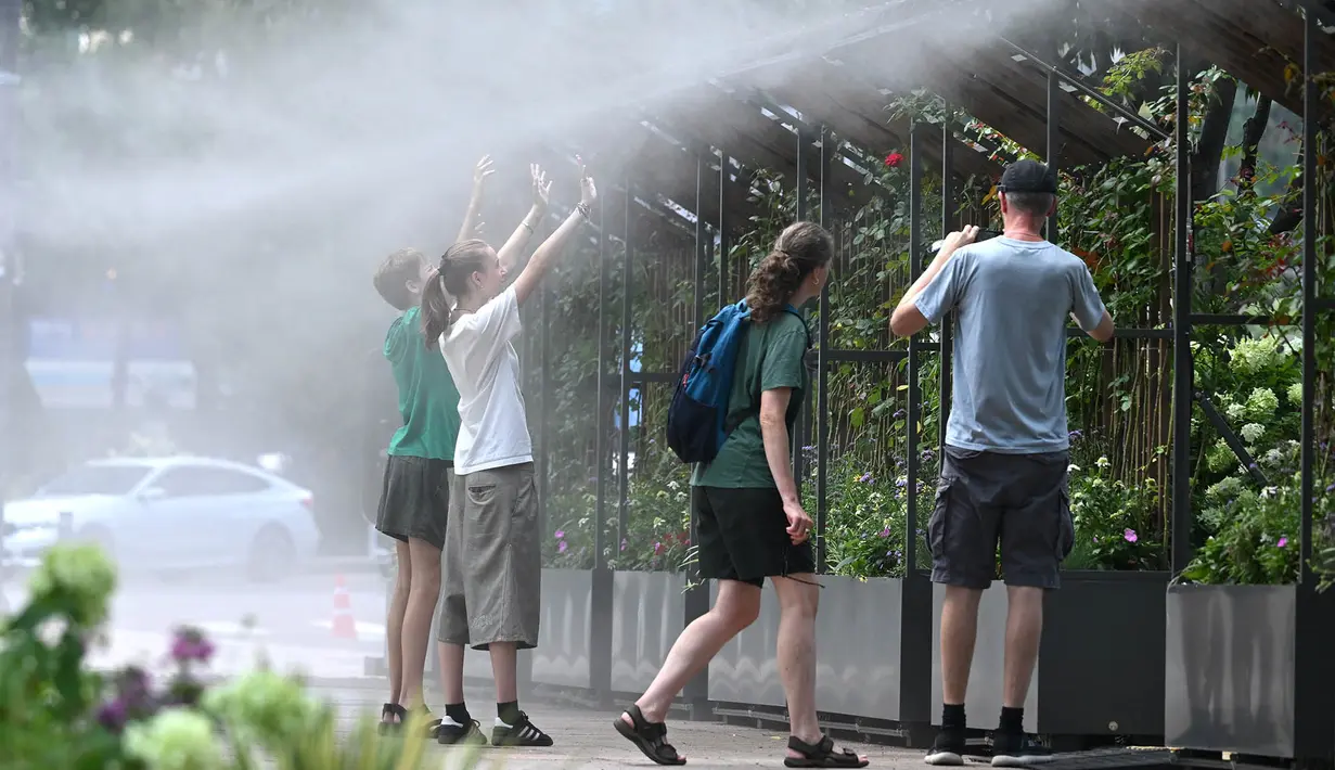 Orang-orang berdiri di zona penyemprotan kabut untuk mendinginkan diri di sebuah jalan di Seoul, Korea Selatan, Senin, 3 Agustus 2026. (AFP/  Jung Yeon-je)